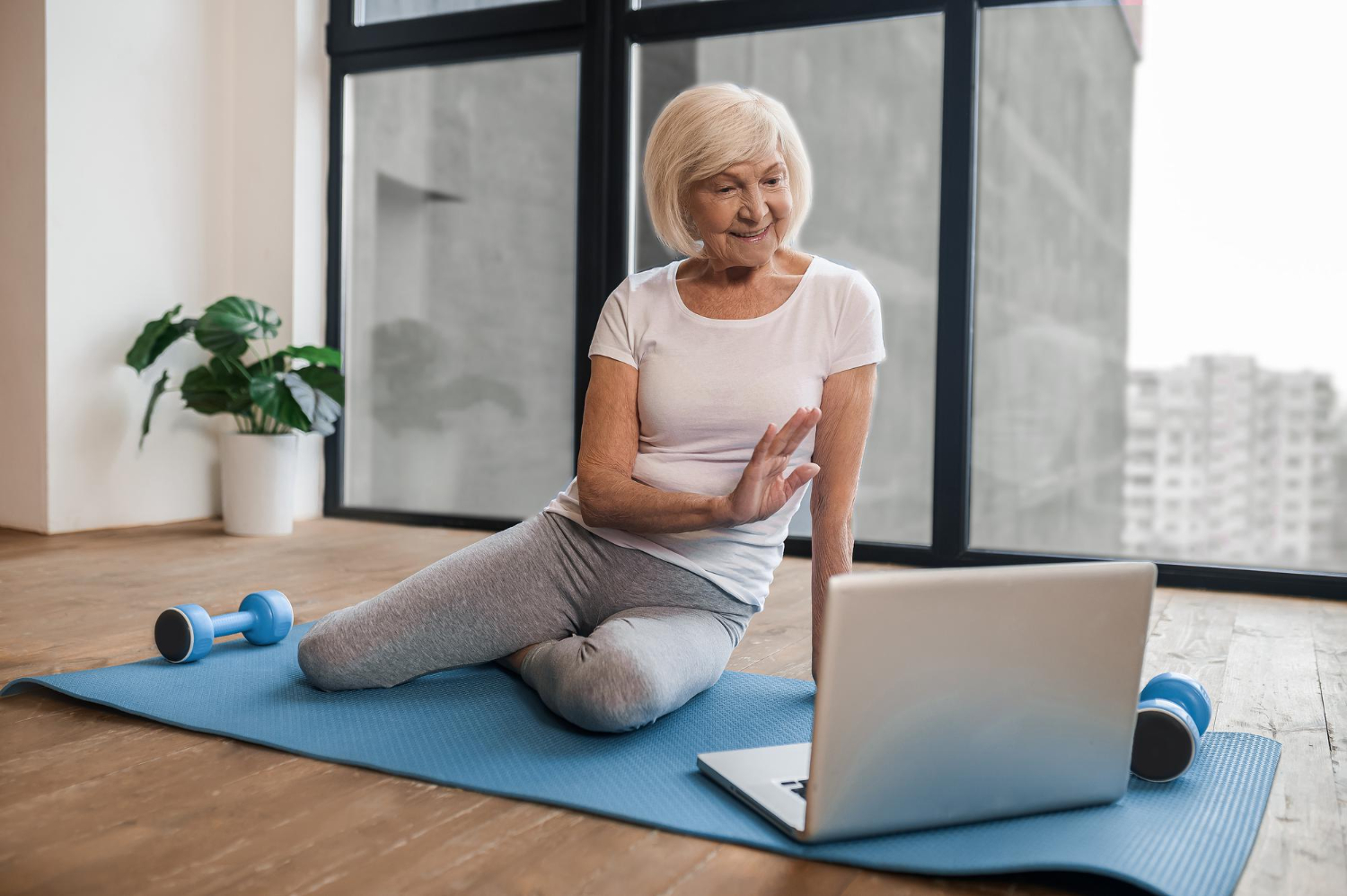 A woman taking part in an online exercise session at home, following along on her laptop