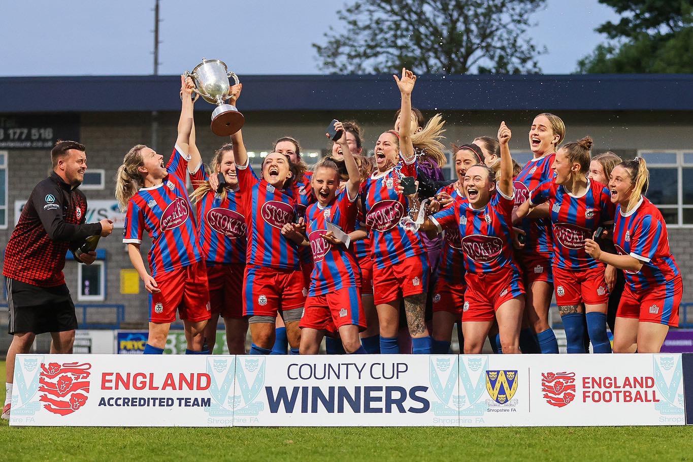 A football team celebrating with the County Cup trophy